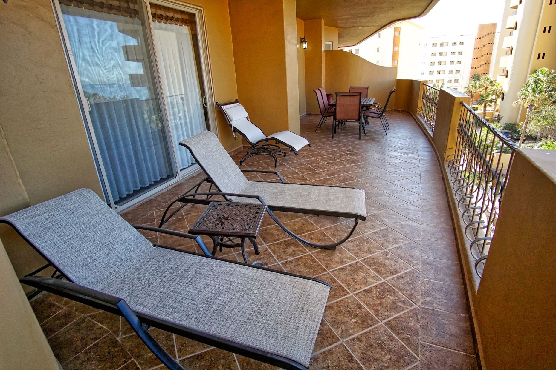 Large patio with chaise lounges nd a dining table as well.