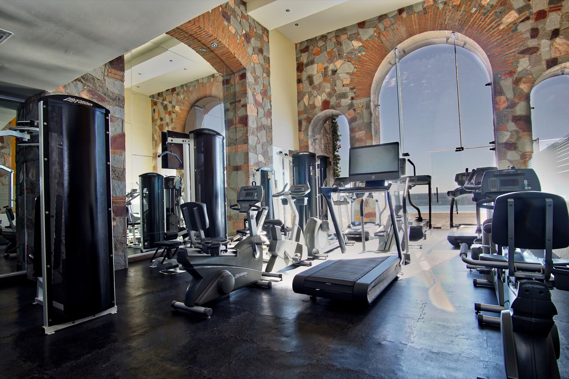 Stately gym with many aerobic machines, along with free weights and Nautilus eqiuipment.