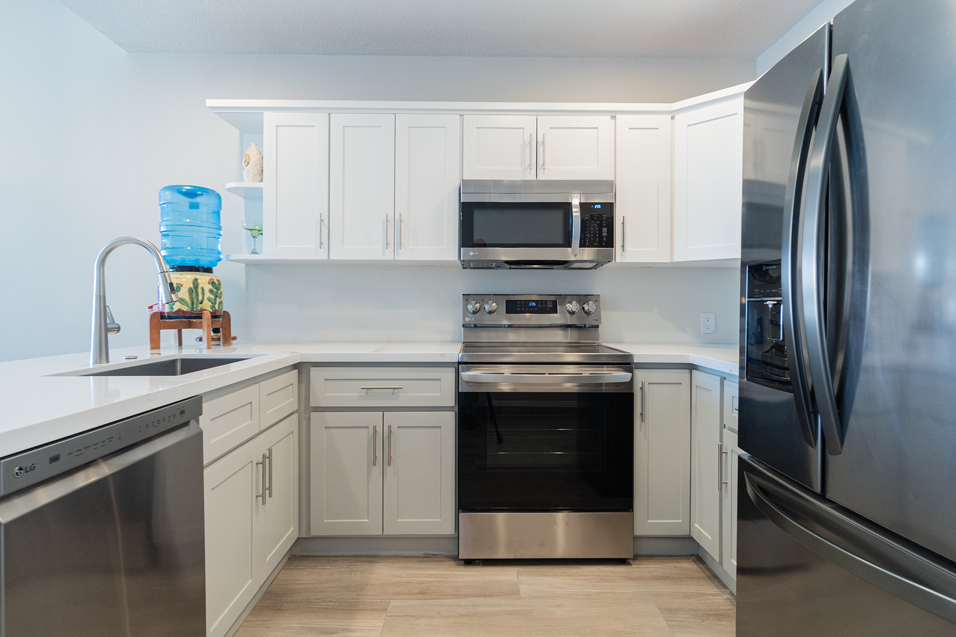 Stainless steel appliances and gleaming white counter tops in the kitchen.
