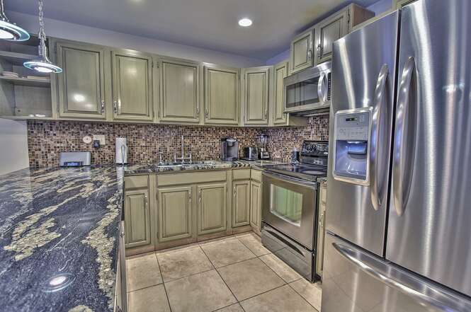 View of the kitchen with new stainless steel appliances, granite counters, docking station, Kurig, and 3-bar seats