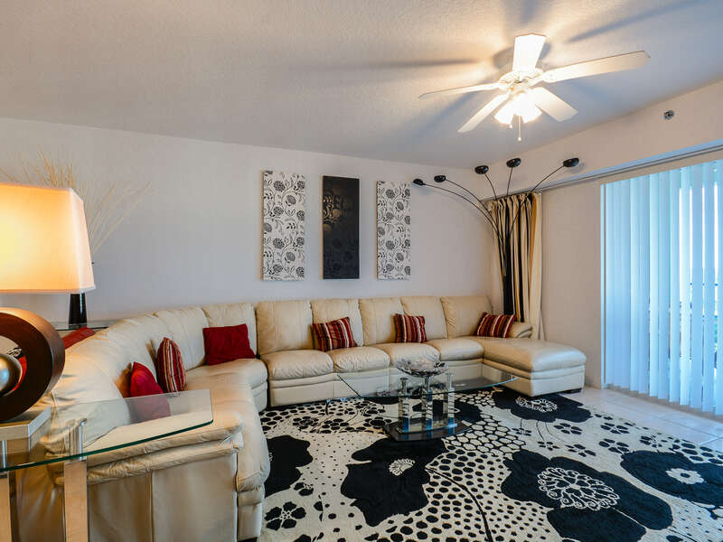 Living Room with Leather Wrap Around Couch and Access to the Private Balcony at Ocean Walk Condo New Smyrna
