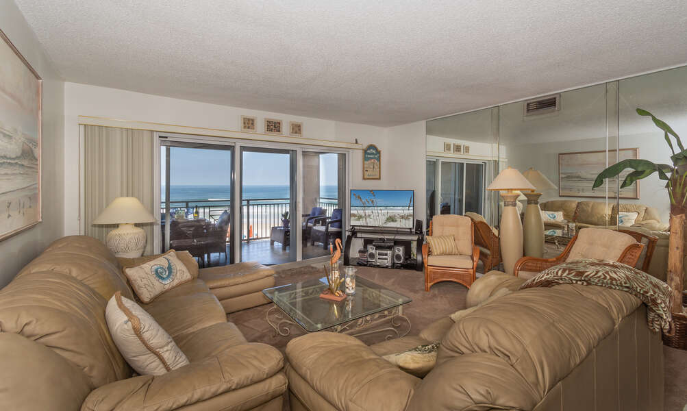 Oceanfront living room with leather sofa sleeper, loveseat and ottoman, large flat screen TV and DVD player.