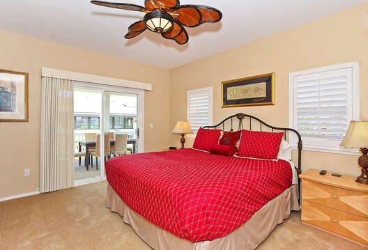 Bedroom with Large Bed, Nightstands, Lamps, Ceiling Fan, and Patio Sliding Doors.