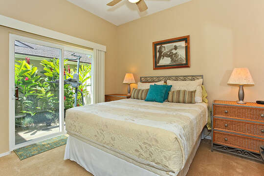 Bedroom with Large Bed, Nightstands, Lamps, Patio Sliding Doors, and Ceiling Fan.