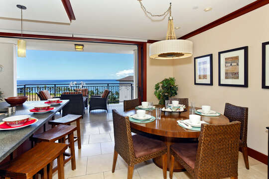 Dining Table, Chairs, Kitchen Island with Stools, and a View of the Ocean from the Balcony.