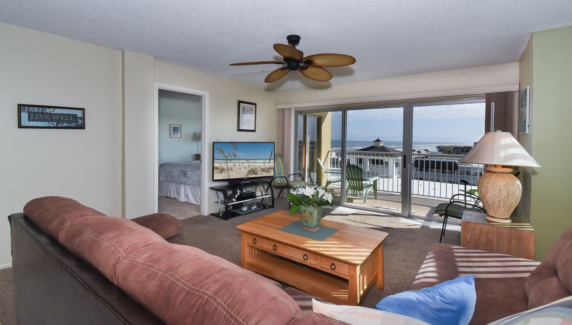 Living area of this private condo in New Smyrna Beach, with ample seating, Flat-screen TV, and coffee table.