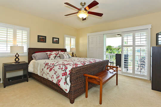 Bedroom with Large Bed, Dresser, TV, Balcony Sliding Doors, and Ceiling Fan.