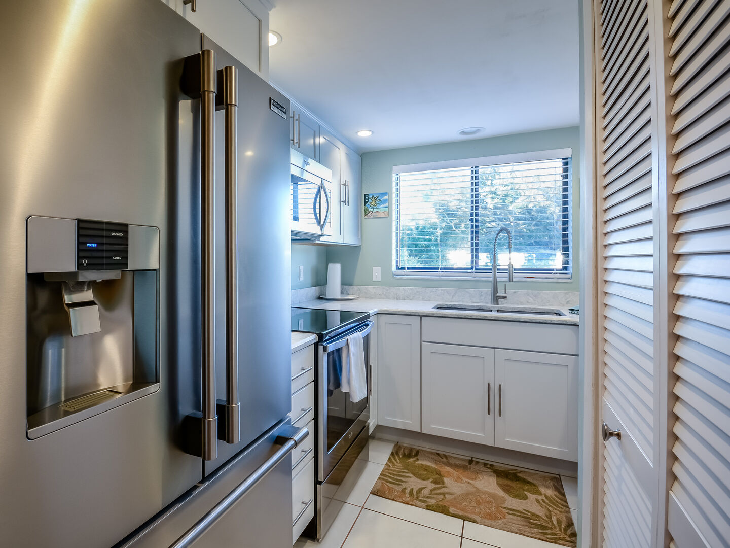 The fully equipped kitchen with double door fridge, oven range, microwave, and sink.
