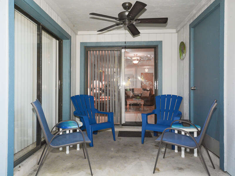 Private patio of this Pet-Friendly Condo in New Smyrna Beach FL with ceiling fan and chairs.