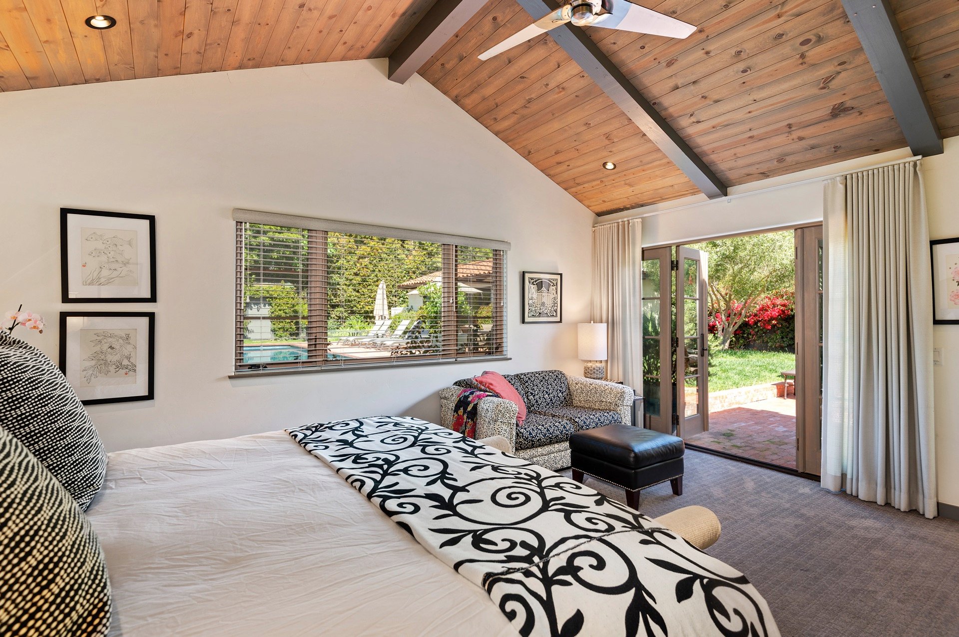 The master suite has a sliding door with curtains that lead to the backyard pool area.