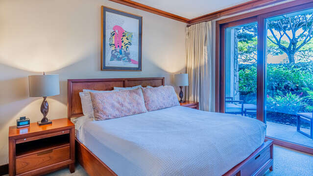 Master Bedroom of this vacation rental in Ko Olina Oahu, complete with large bed, dual nightstands on either side with lamps, and dresser with TV.