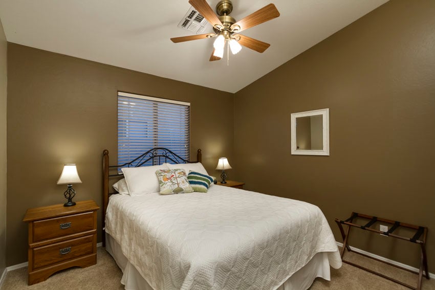 guest bedroom has a queen bed, ceiling fan, two nightstands with lamps.