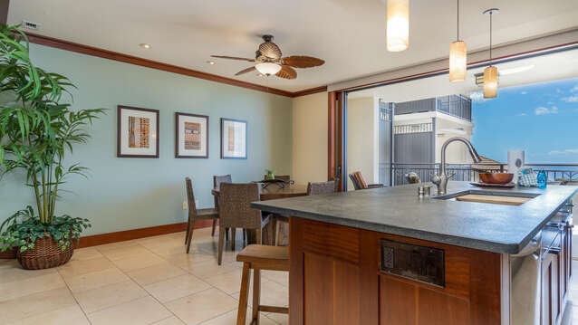 Kitchen with Bar, Oven, Refrigerator, Dining Table, Chairs, and Ceiling Fan.