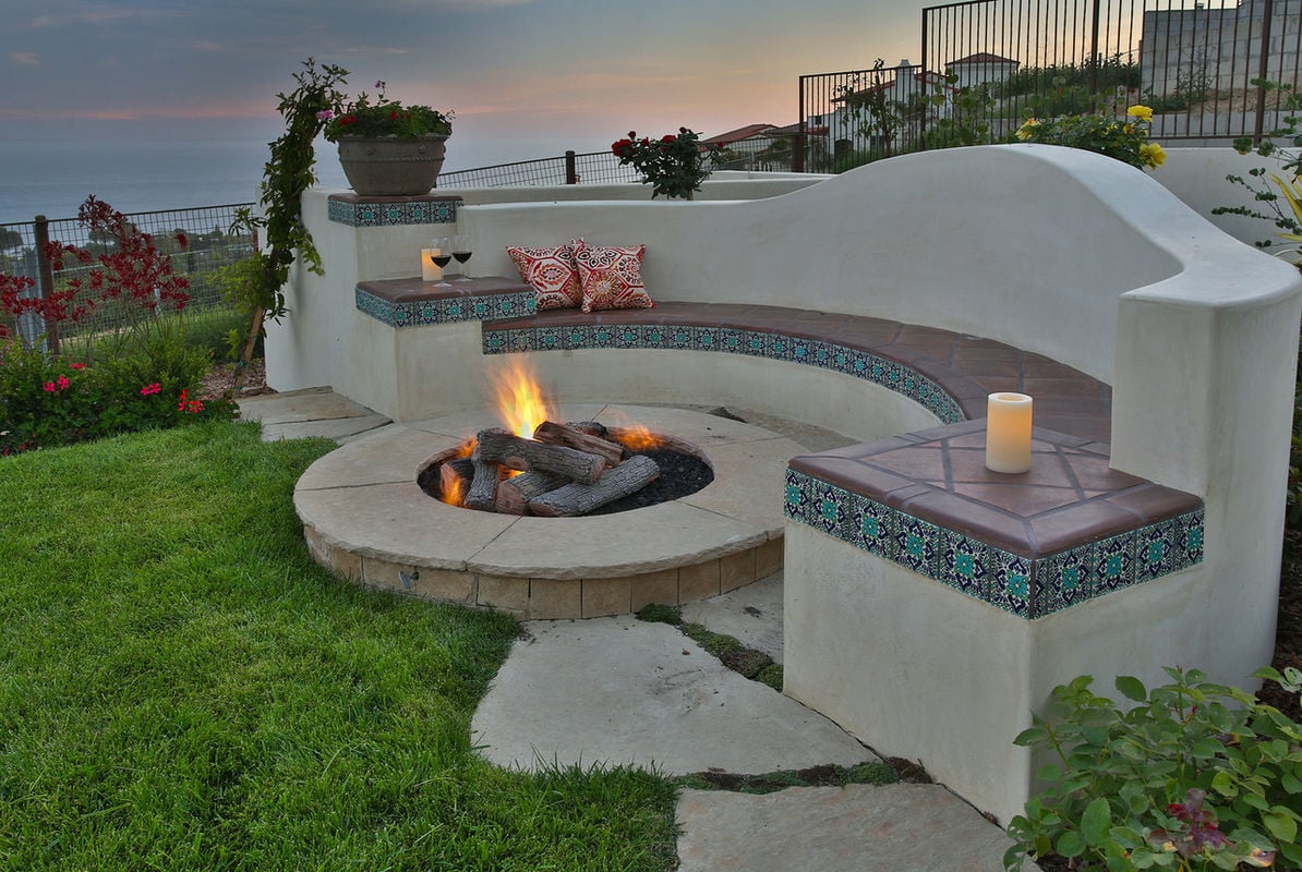 Fire pit is adjacent to pool and outdoor grill center