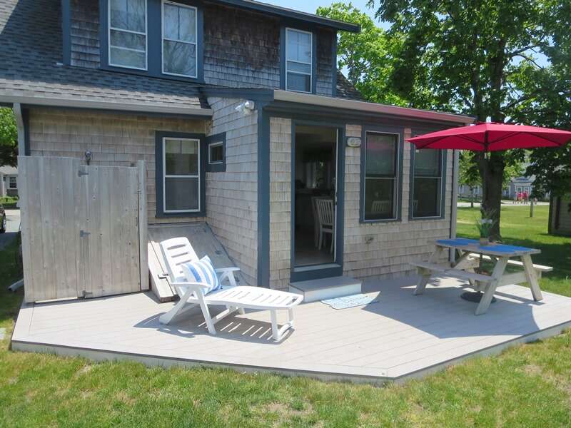 Outdoor picnic table with an umbrella and a chaise lounge. Also in the backyard, an enclosed outdoor shower - 36 Cross Street Harwich Port Cape Cod New England Vacation Rentals