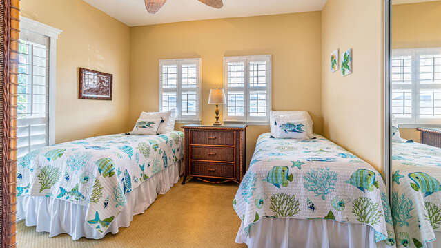 Two full beds side by side in one of this rentals bedrooms, with a nightstand in-between.