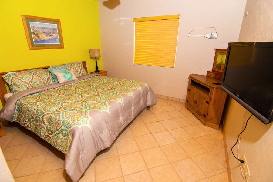 Second guest room with king sized bed, flat screen TV and shared bathroom in the hall.