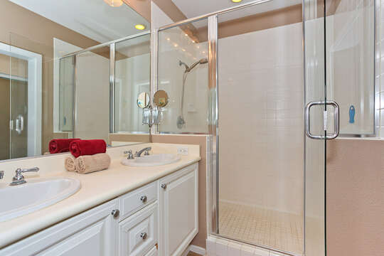 Master Bathroom with walk-in shower, two sinks side by side, towels, and large mirror.