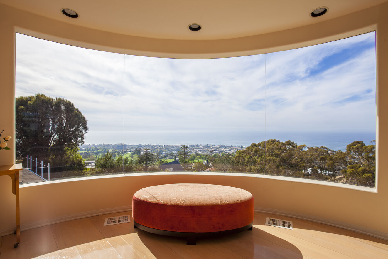 Curved glass windows offer panoramic views of the Pacific Ocean and La Jolla Village