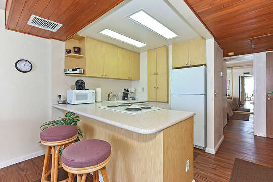 Kitchen with Counter, Stools, Refrigerator, Coffee Maker, and Microwave.