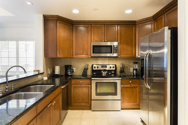Beautiful granite counter tops line the kitchen and surround the stainless steel appliances