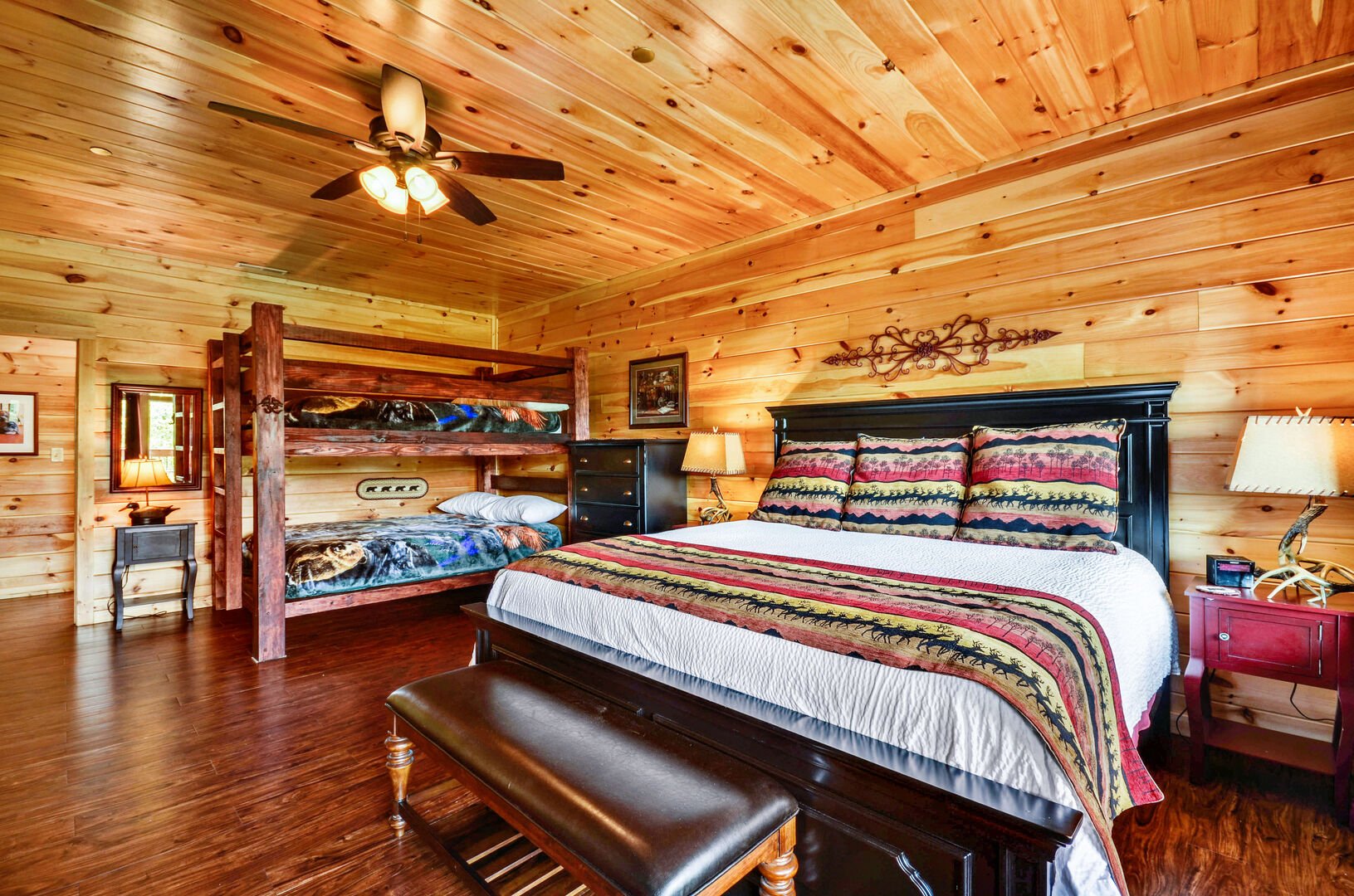 Full bed and bunk bed in a bedroom, with dressers and nightstands beside them.