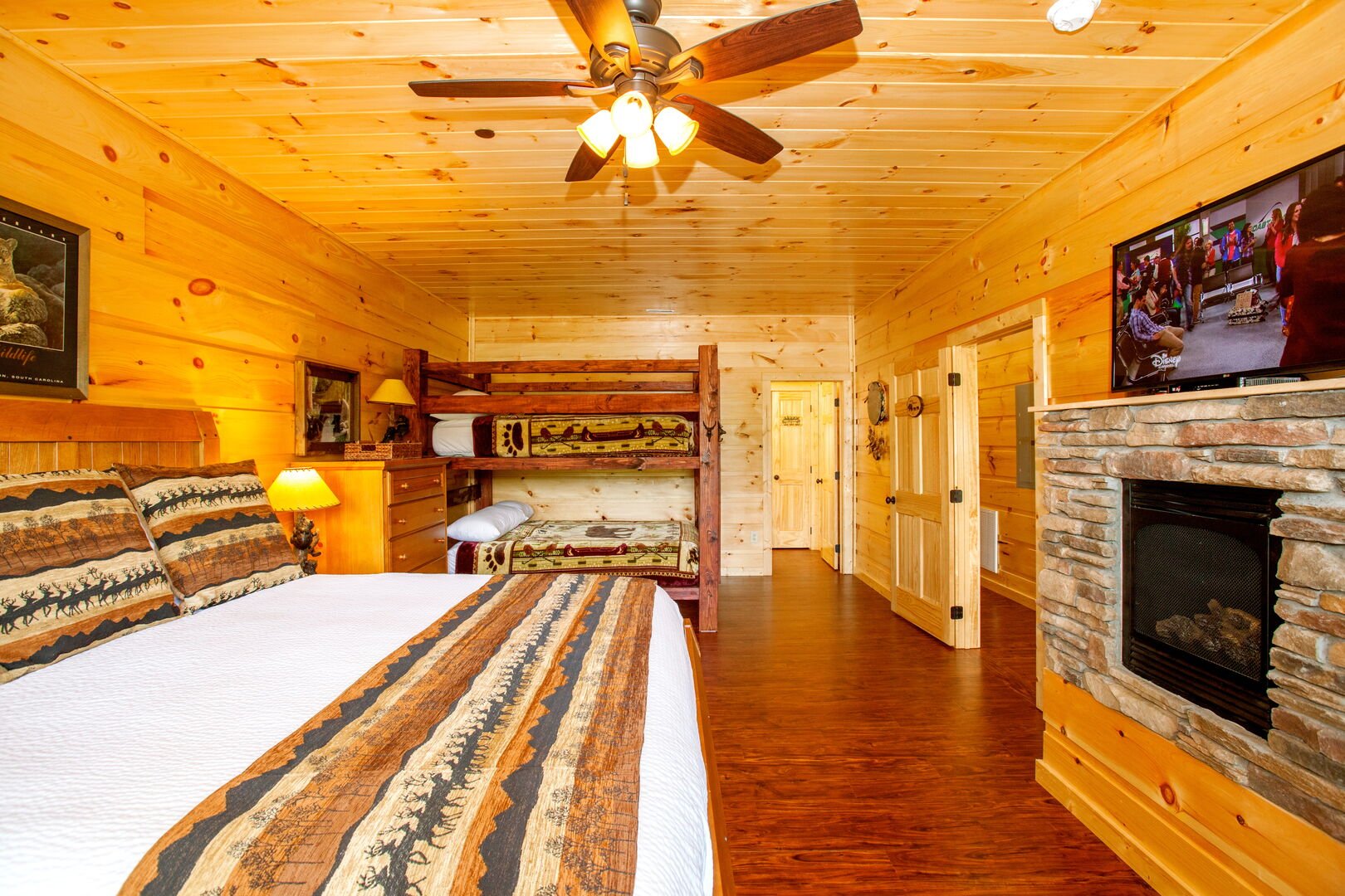 Bunk room with large bed, bunk-bed, and fireplace with TV above.