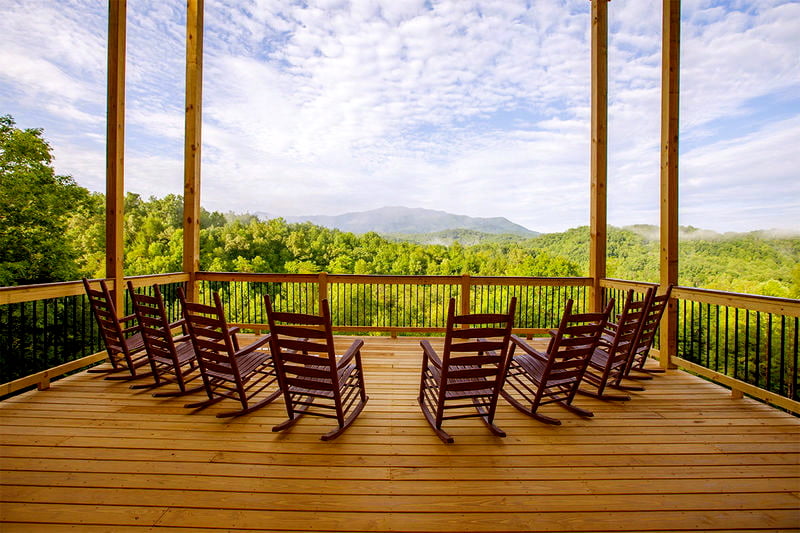 8 rocking chairs on the balcony overlooking forest scenery.
