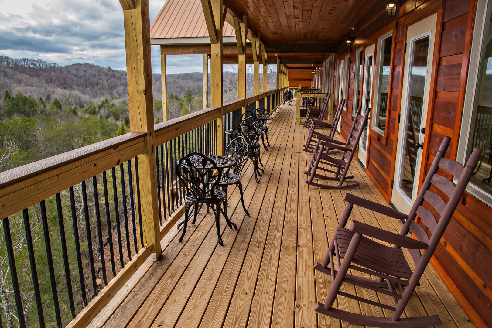 Large Deck with Many Outdoor Tables, Chairs, and Rocking Chairs.