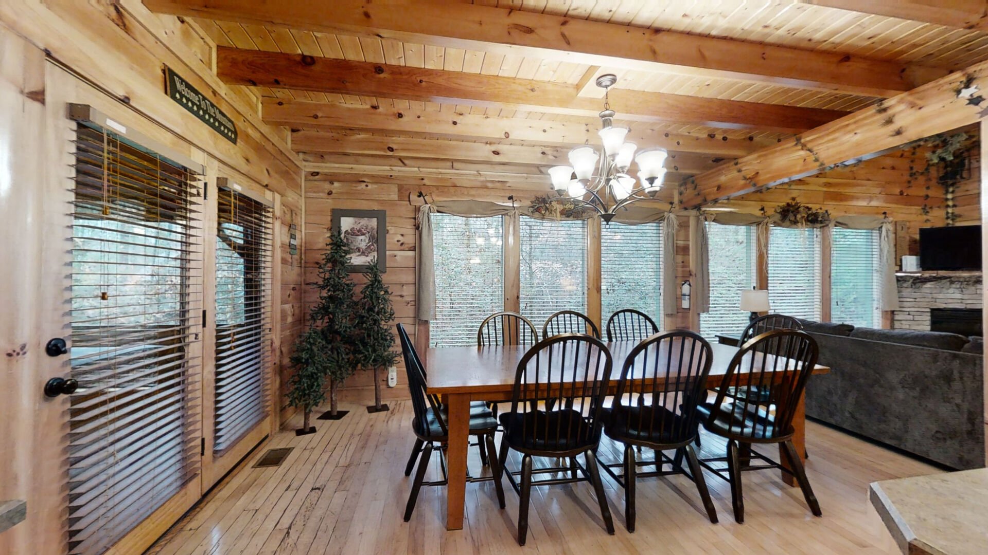 Open concept dining room with seating for eight with floor to ceiling windows and a wooded view