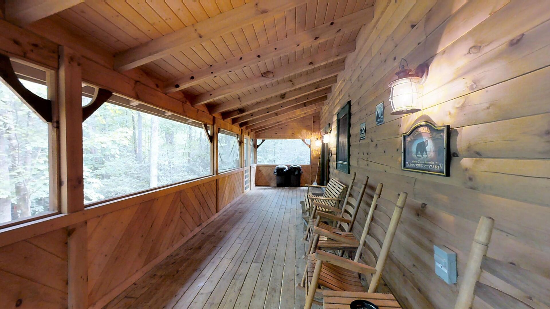 Screened in back yard deck that runs the full length of the cabin with rocking chairs, hot tub, swing overlooking large private yard