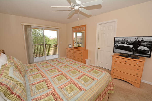 Master bedroom showing flatscreen TV, balcony and bathroom entry