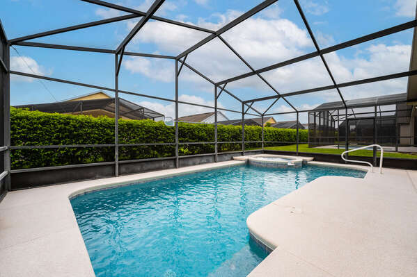 Spacious pool deck with screen enclosure and safety rails for easy entry into pool