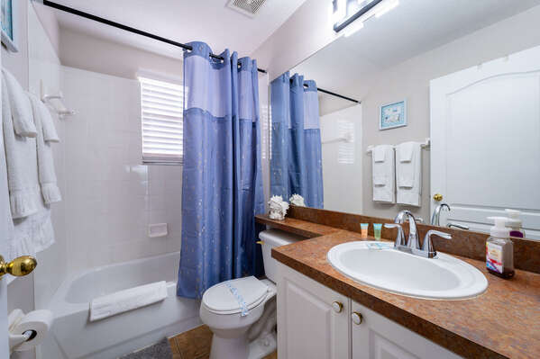 Shared bathroom with shower/tub combo and single sink vanity.