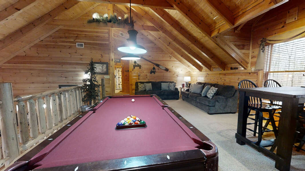 Large game room located on second floor with pool table, poker table, retro gaming system with 60 games, two charcoal couches along with vaulted ceilings