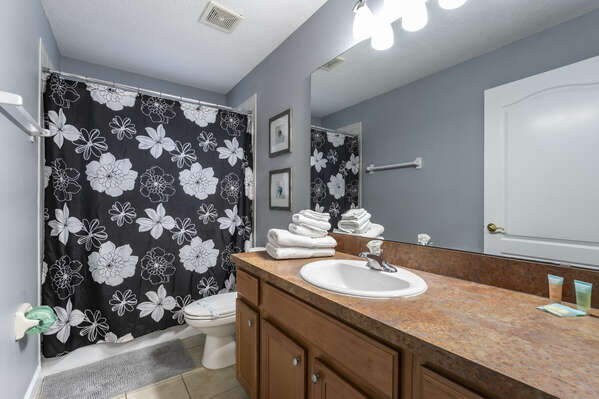Shared bathroom with shower tub combo and single sink vanity