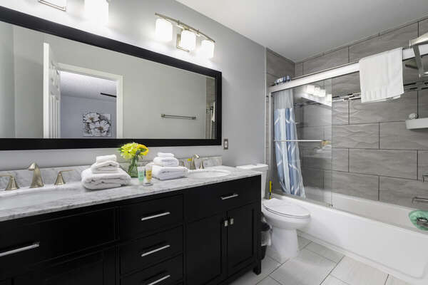 Shared loft bath showing shower/ tub combo, toilet, and double sink vanity