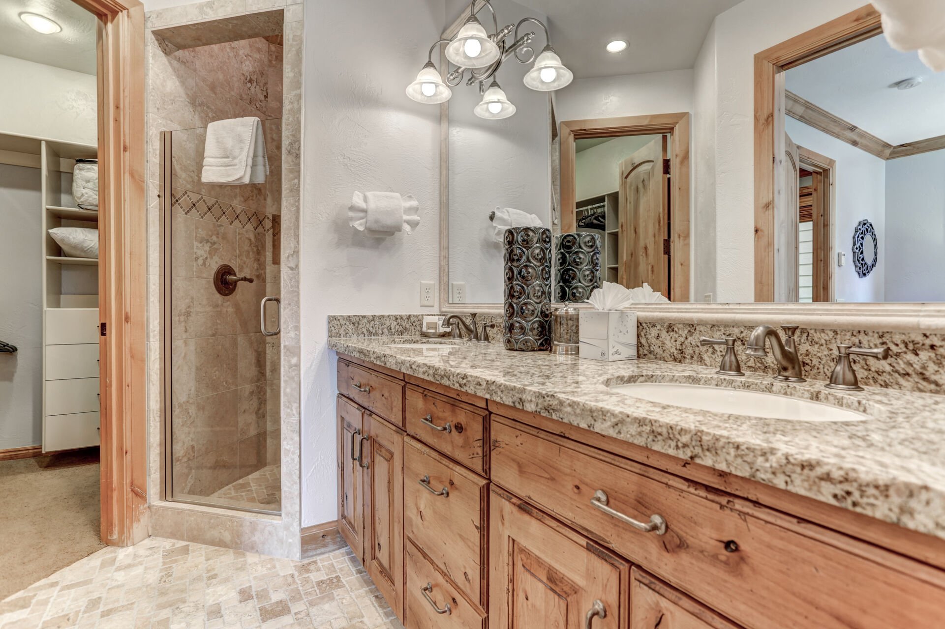 Master bathroom with dual vanities, stone shower and large walk-in closet with built-in dresser