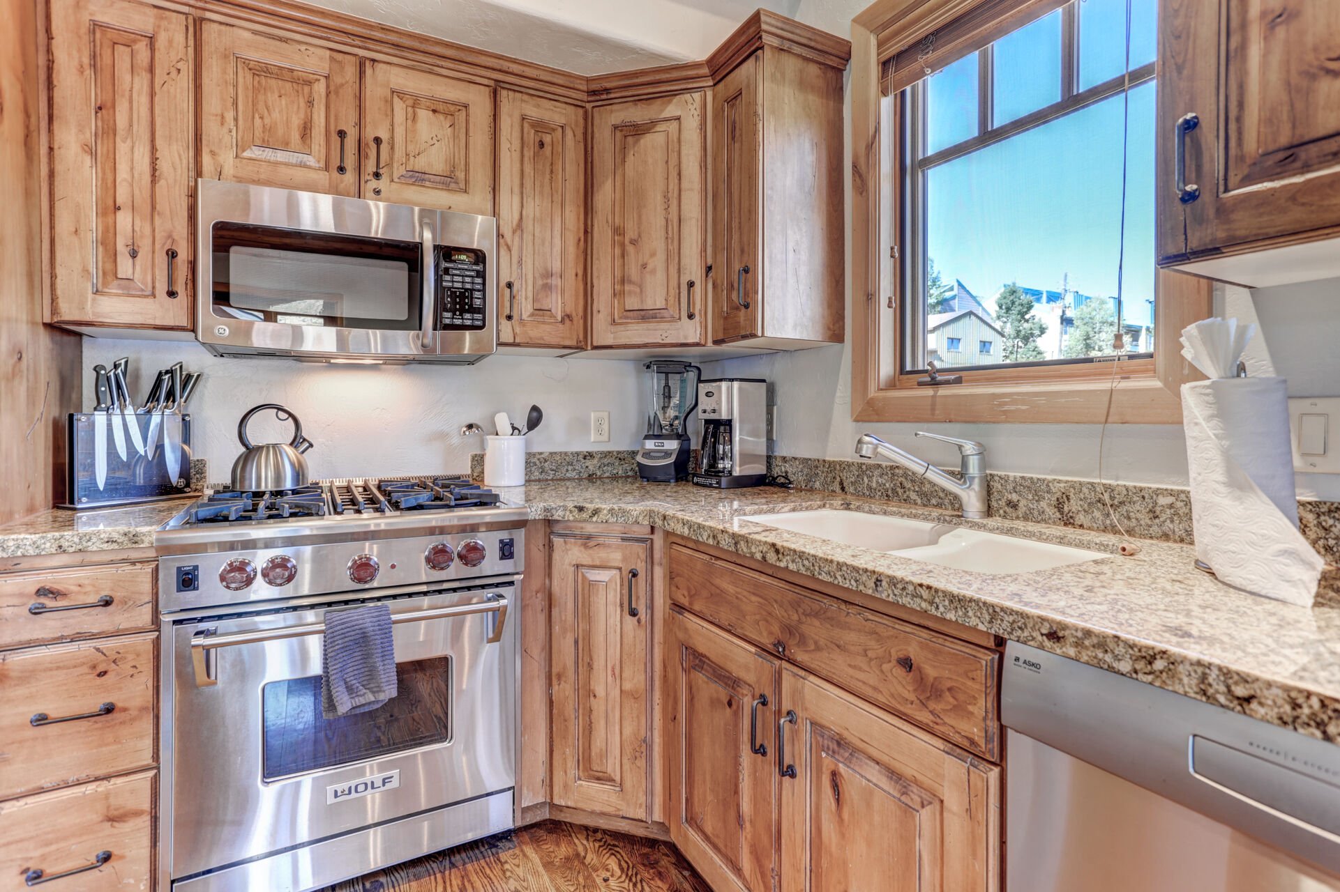 Gourmet display kitchen with Viking refrigerator, 5-burner gas stove, granite counters, and island with 4-bar seats