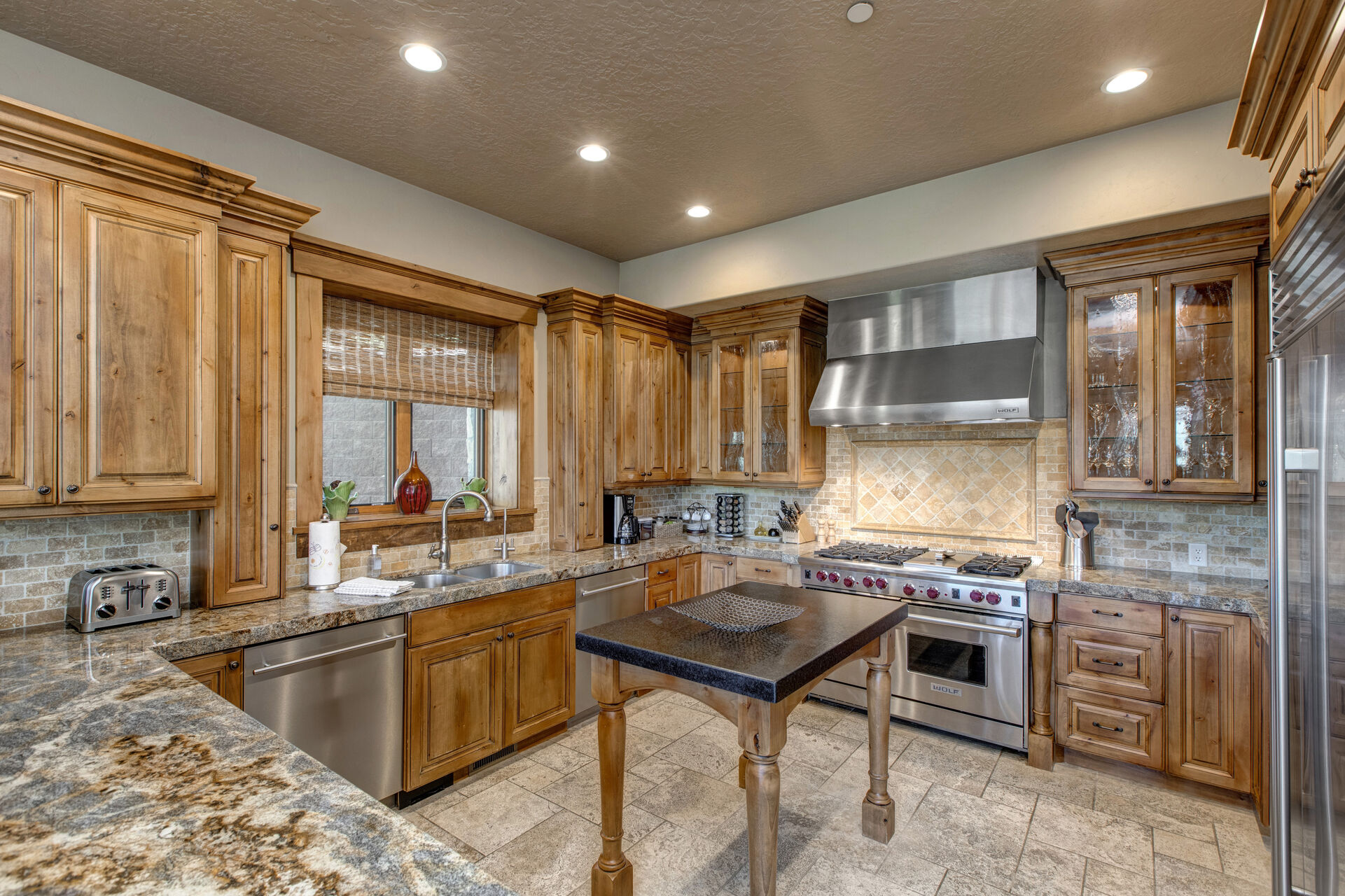 Kitchen with granite island, stone countertops, stainless steel appliances, Wolff stove, walk-in pantry, and bar seating for three