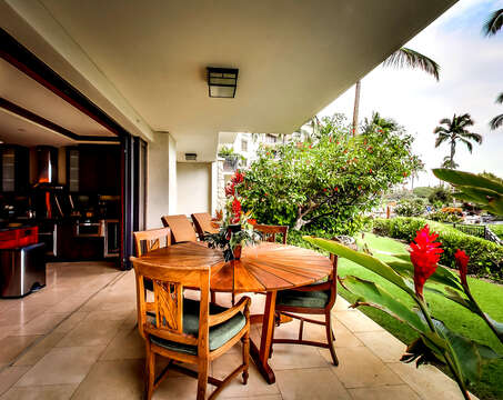 Lanai view with seating and loungers in front of beautiful greens and garden.