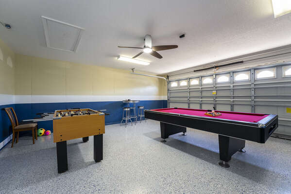 Garage converted game room showing pool and foosball tables with seating.