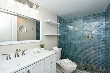 En suite master bathroom with granite counter top, tile floors and glass tile walk-in shower