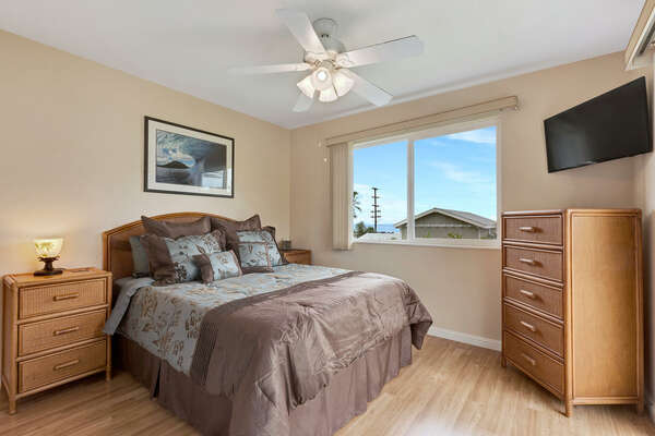 Master Bedroom of this Kona Hawaii vacation rental with Queen Bed, dresser, wall-mounted TV and nightstand.