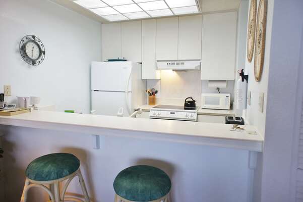 Kitchen with breakfast bar, counter stools, refrigerator, and microwave