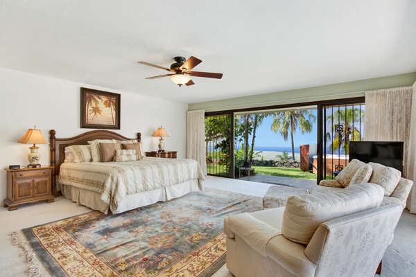 Primary Bedroom of this Kona Hawaii vacation rental with King Bed and a large glass door opening to the backyard.