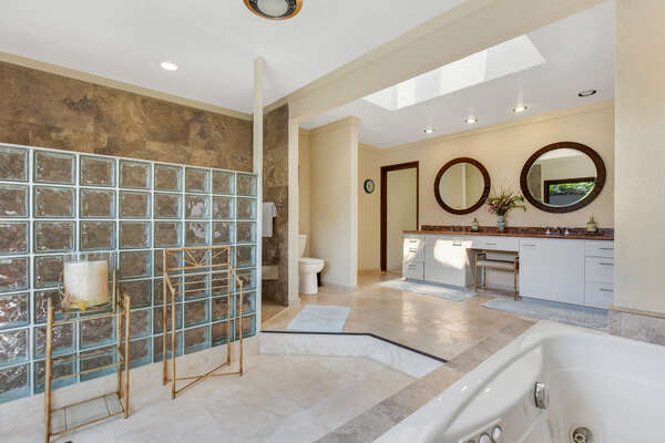 The Primary bathroom of this Kona Hawaii vacation rental with double vanity sinks, a walk-in shower, and a spa tub.