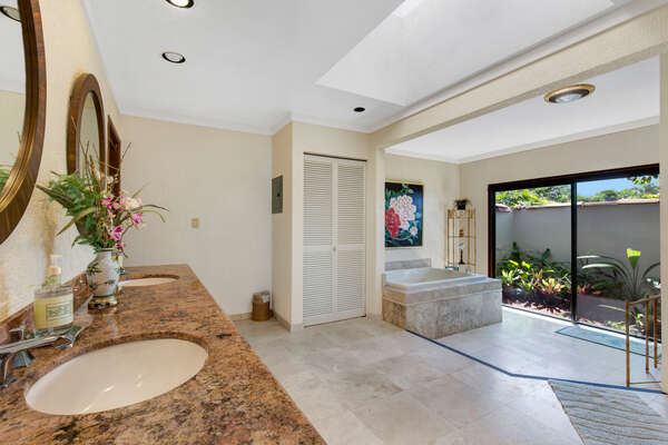 Master Bathroom with double vanity sinks, a spa tub, and door to the backyard.