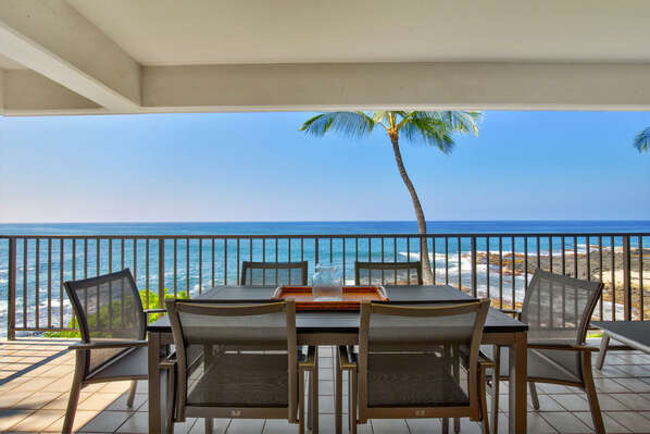 Table and chairs on the lanai of this oceanfront vacation rental, with a view over the ocean.