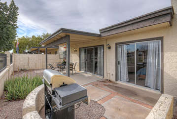 Covered patio in backyard includes propane gas grill for outdoor grilling.